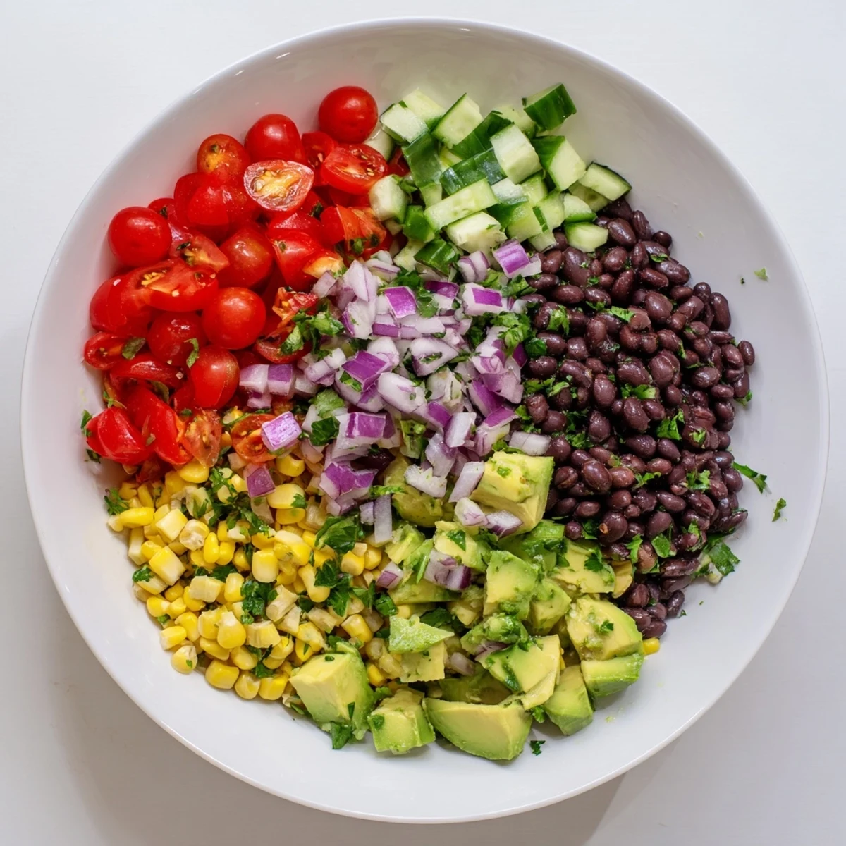 Colorful chopped black bean salad with crisp corn, bell peppers, creamy avocado in bowl