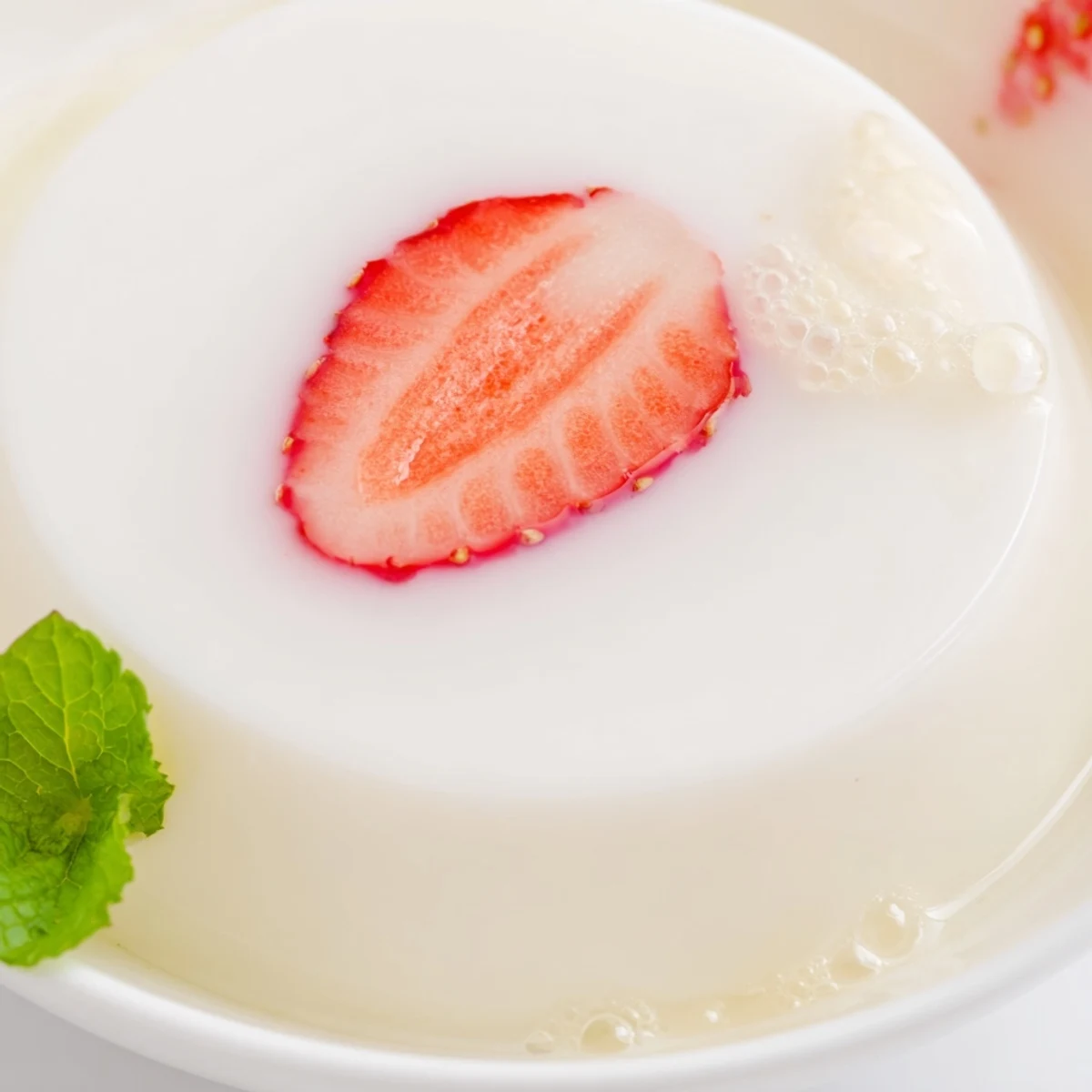 Creamy white milk yokan topped with fresh red strawberry halves in a rectangular mold