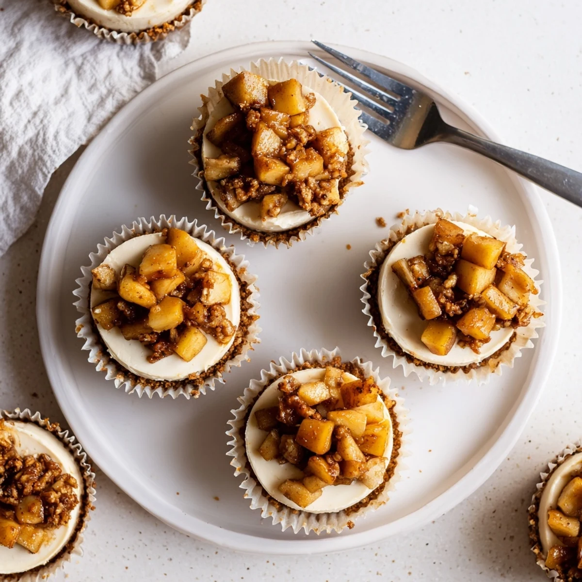 Golden brown apple crisp mini cheesecakes topped with warm spiced cinnamon apples and crumbly oat topping
