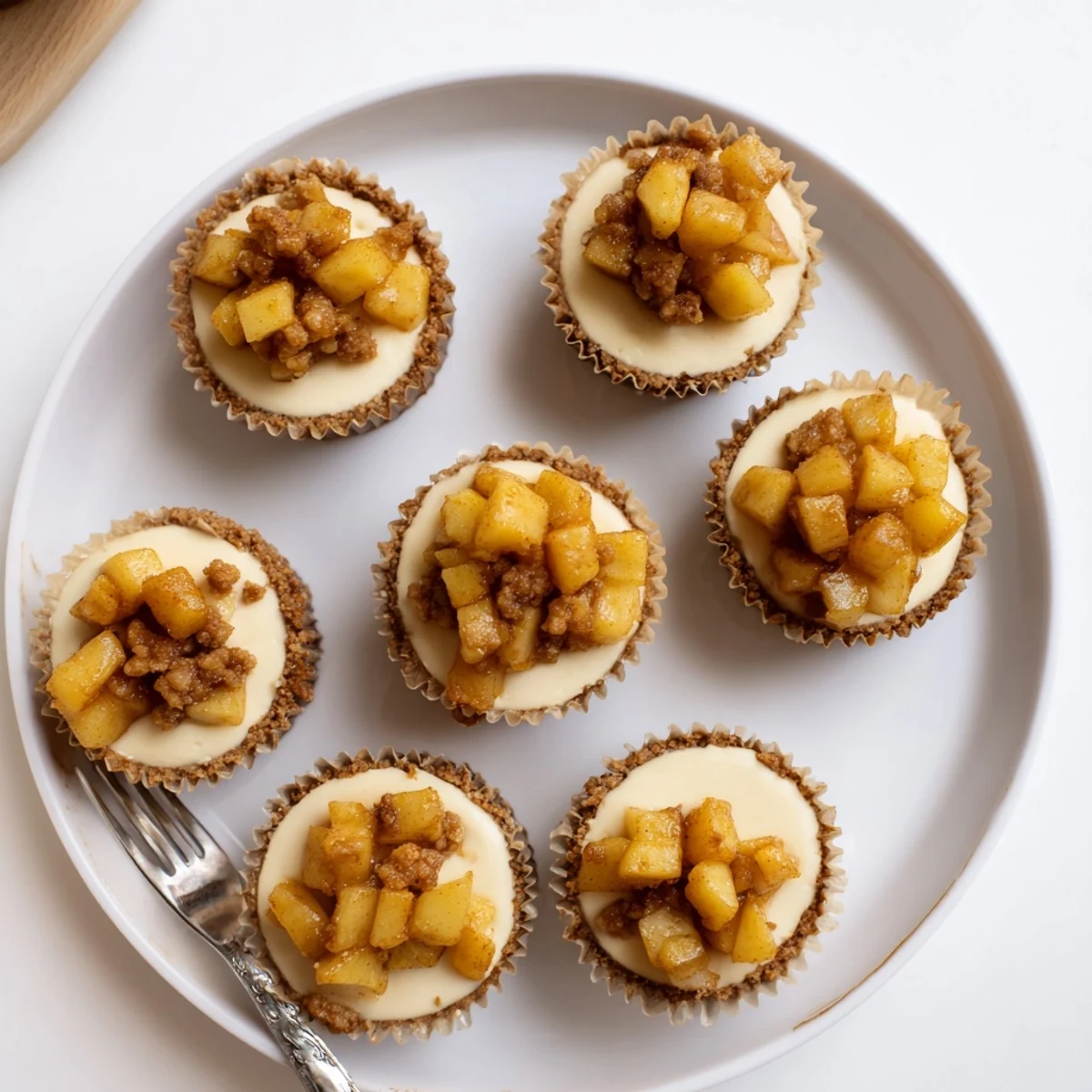 Individual creamy cheesecakes featuring tender baked apples with brown sugar and buttery streusel in muffin cups
