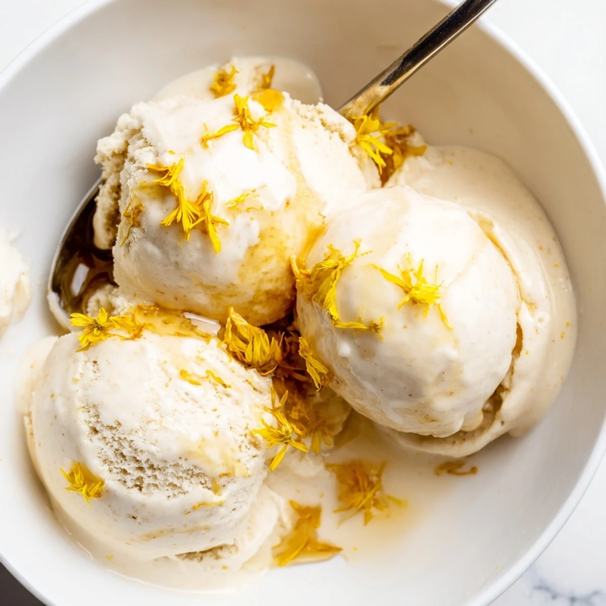Creamy dandelion honey ice cream scoop topped with golden petals and honey drizzle