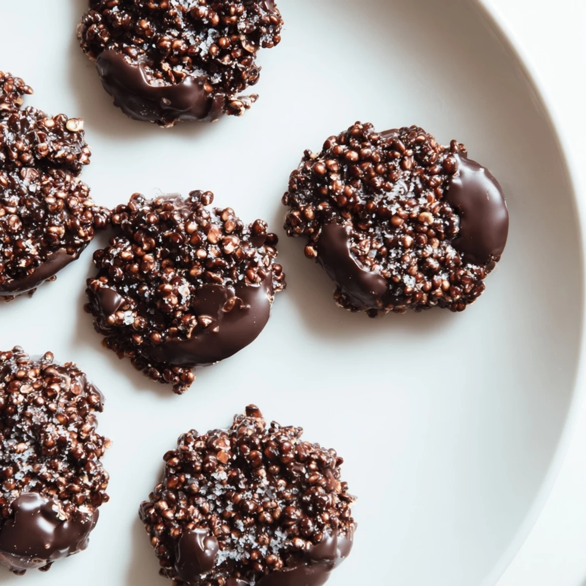 Bite-sized dark chocolate quinoa crisps arranged on a serving plate for easy snacking