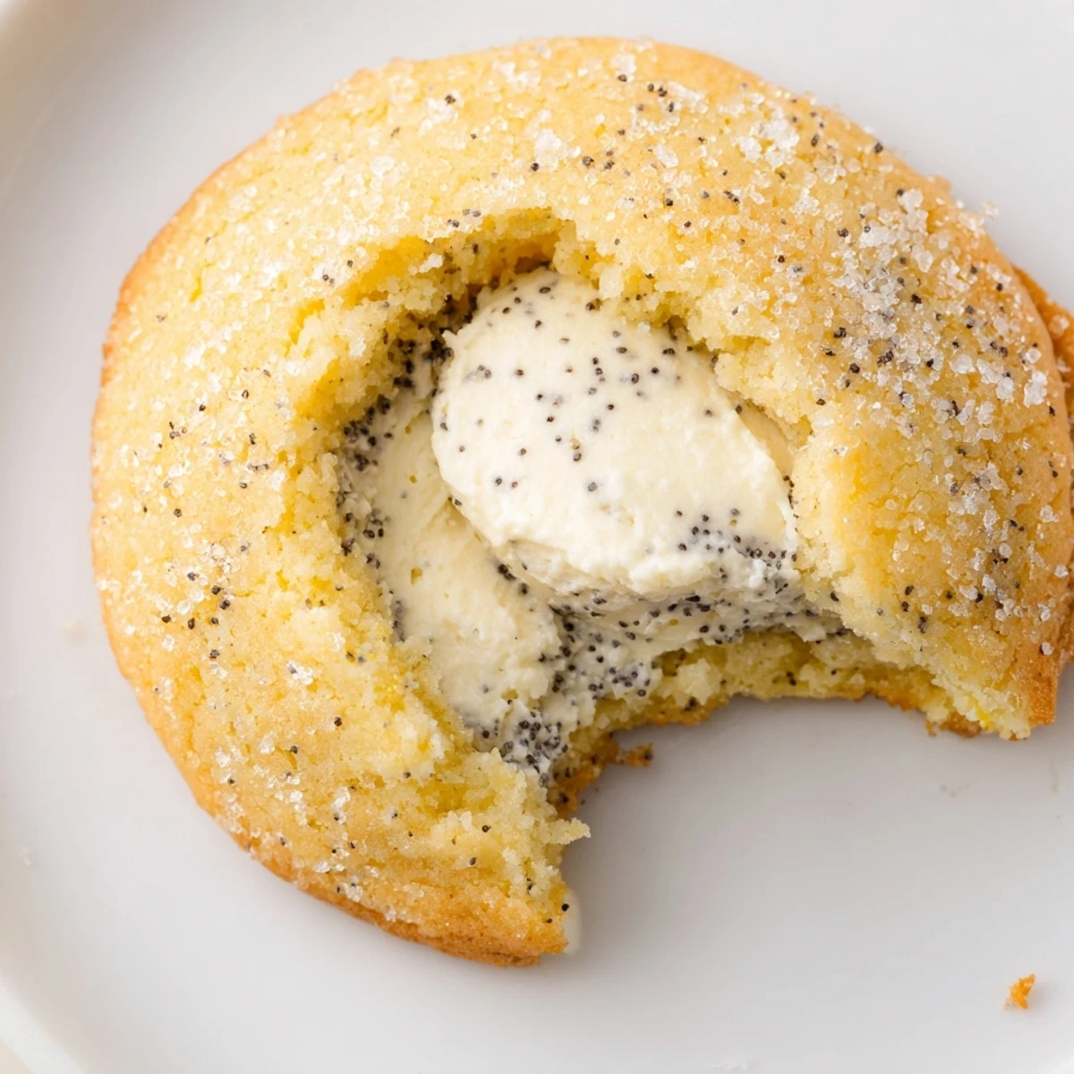 Golden lemon poppy seed cheesecake cookies with creamy centers on white plate