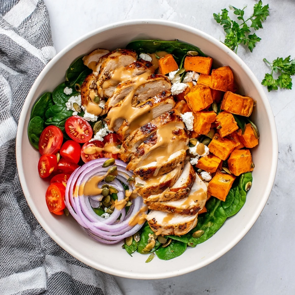 Sliced maple Dijon chicken over colorful roasted vegetables in hearty maple Dijon chicken sweet potato bowls