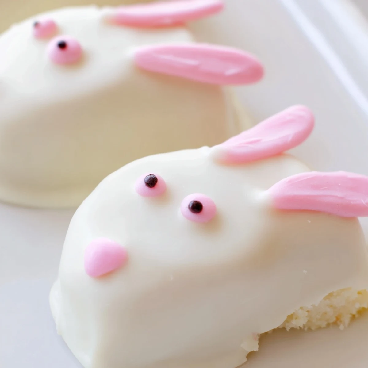 White chocolate bunny cakesicles dipped in smooth coating with pink fondant ears