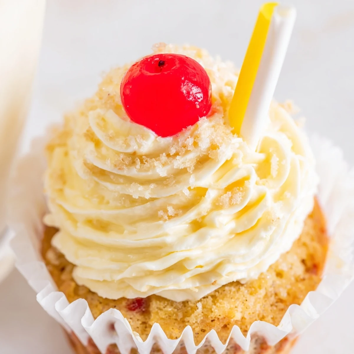 Moist banana milkshake cupcakes topped with creamy vanilla frosting and garnished with bright red cherries