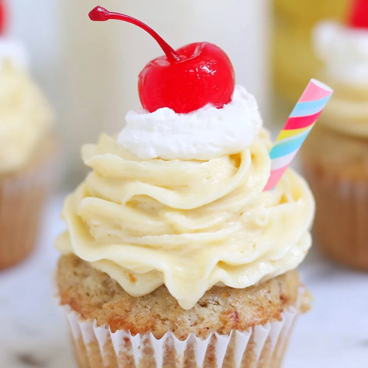 Golden banana milkshake cupcakes with fluffy swirled frosting served on a rustic white ceramic plate