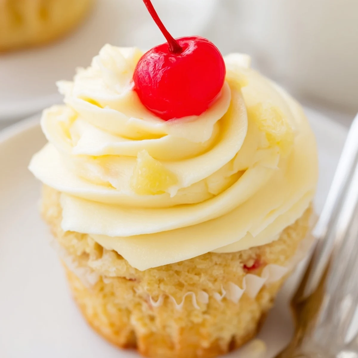 Fluffy pineapple whipped frosting swirled on moist Dole Whip Cupcakes on a bright plate