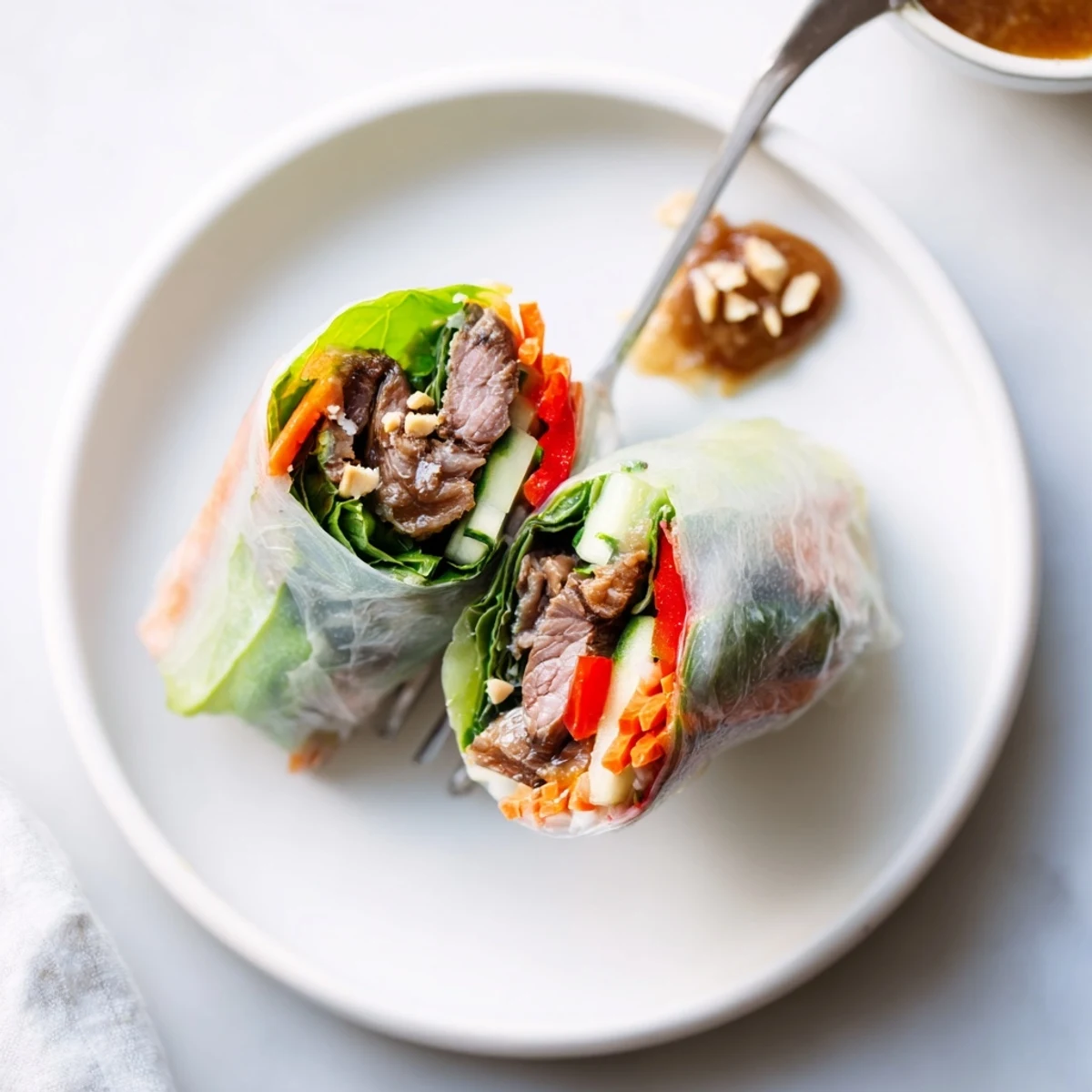 Thai Basil Beef Rolls, handheld halves showing glossy rice paper and savory sauce