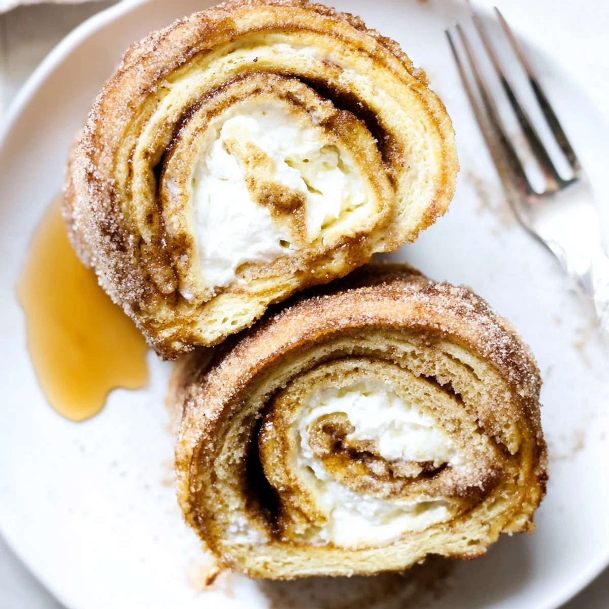 Warm Cinnamon Roll French Toast Roll Ups dusted with cinnamon sugar, gooey cream cheese.