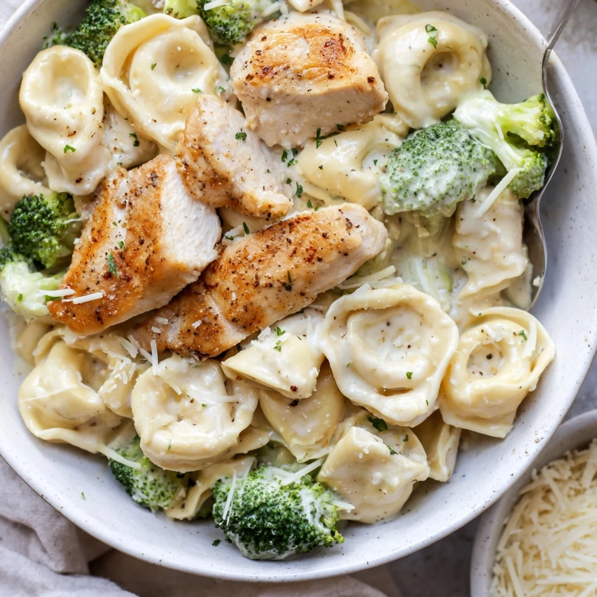 Creamy Garlic Parmesan Tortellini Chicken Broccoli Recipe steaming in skillet, parsley garnish  