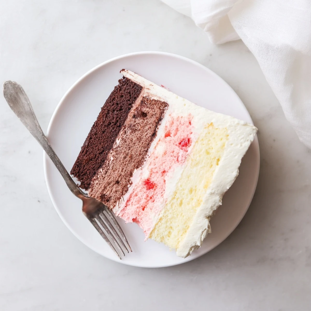 Tri-layer Neapolitan cake dessert showcasing chocolate vanilla and strawberry sponge layers frosted generously with rich creamy buttercream for special occasions