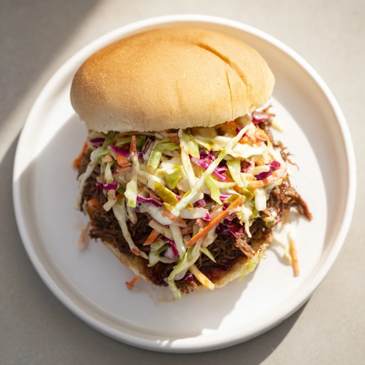 Tender smoky BBQ beef sandwiches piled high with crunchy colorful coleslaw on toasted buns
