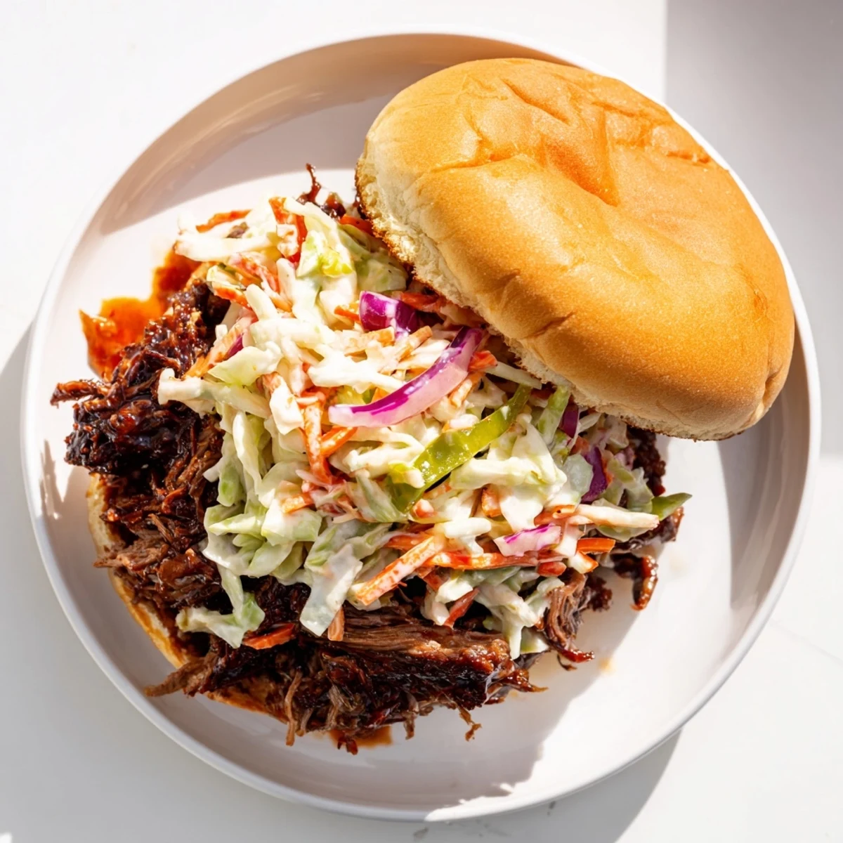 Melt-in-your-mouth BBQ beef sandwich topped with crisp tangy coleslaw and rich smoky sauce