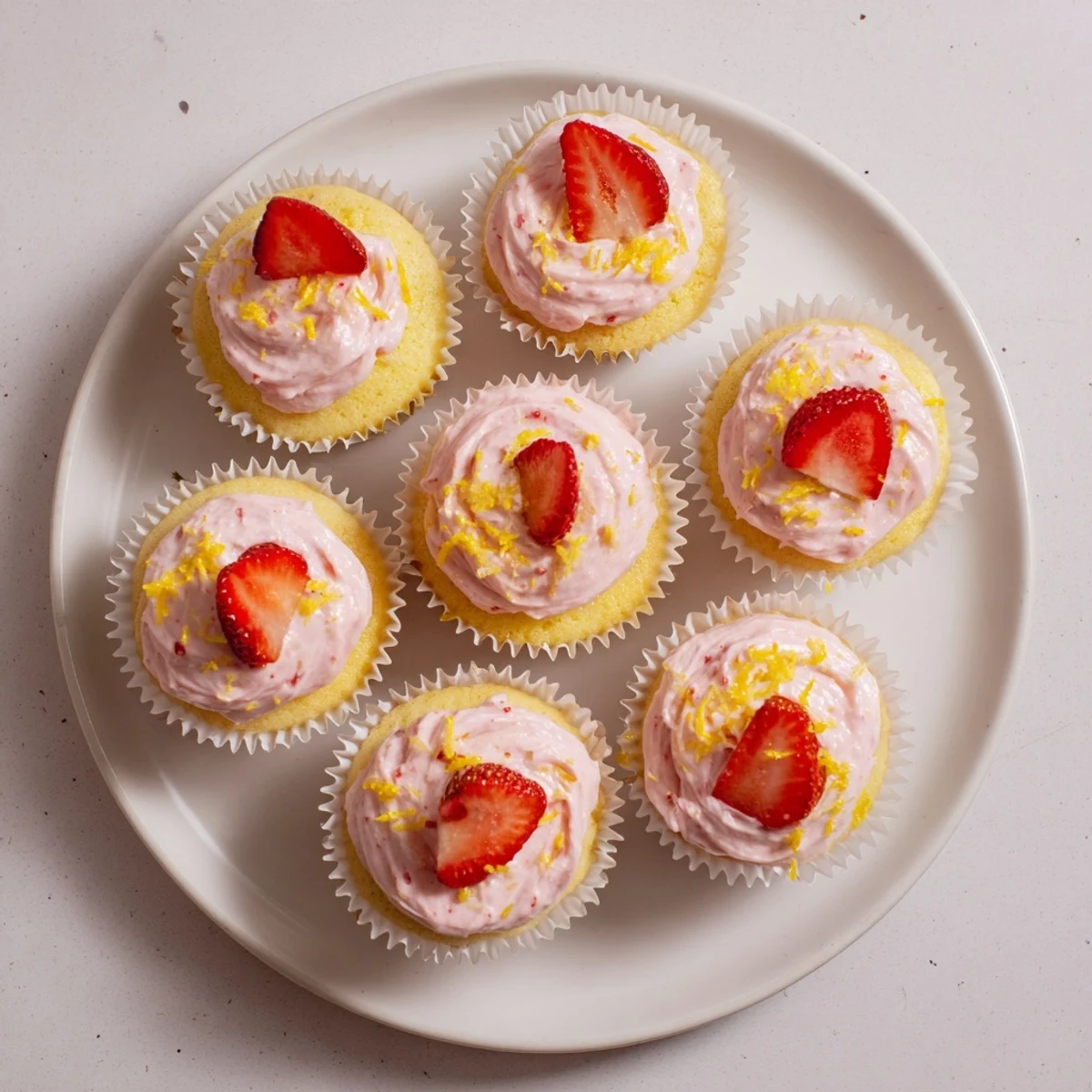 Close up of moist strawberry lemonade cupcakes with luscious pink frosting and fresh berry garnish