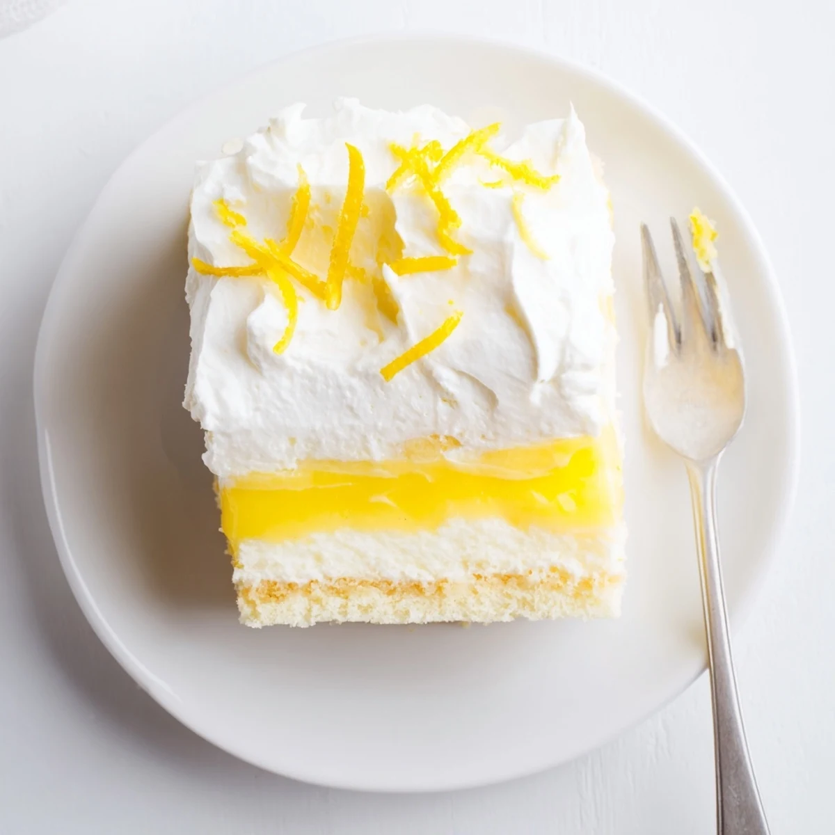 Ultimate lemon lush cake dessert square revealing four distinct layers from golden crust to lemon curd and airy whipped cream