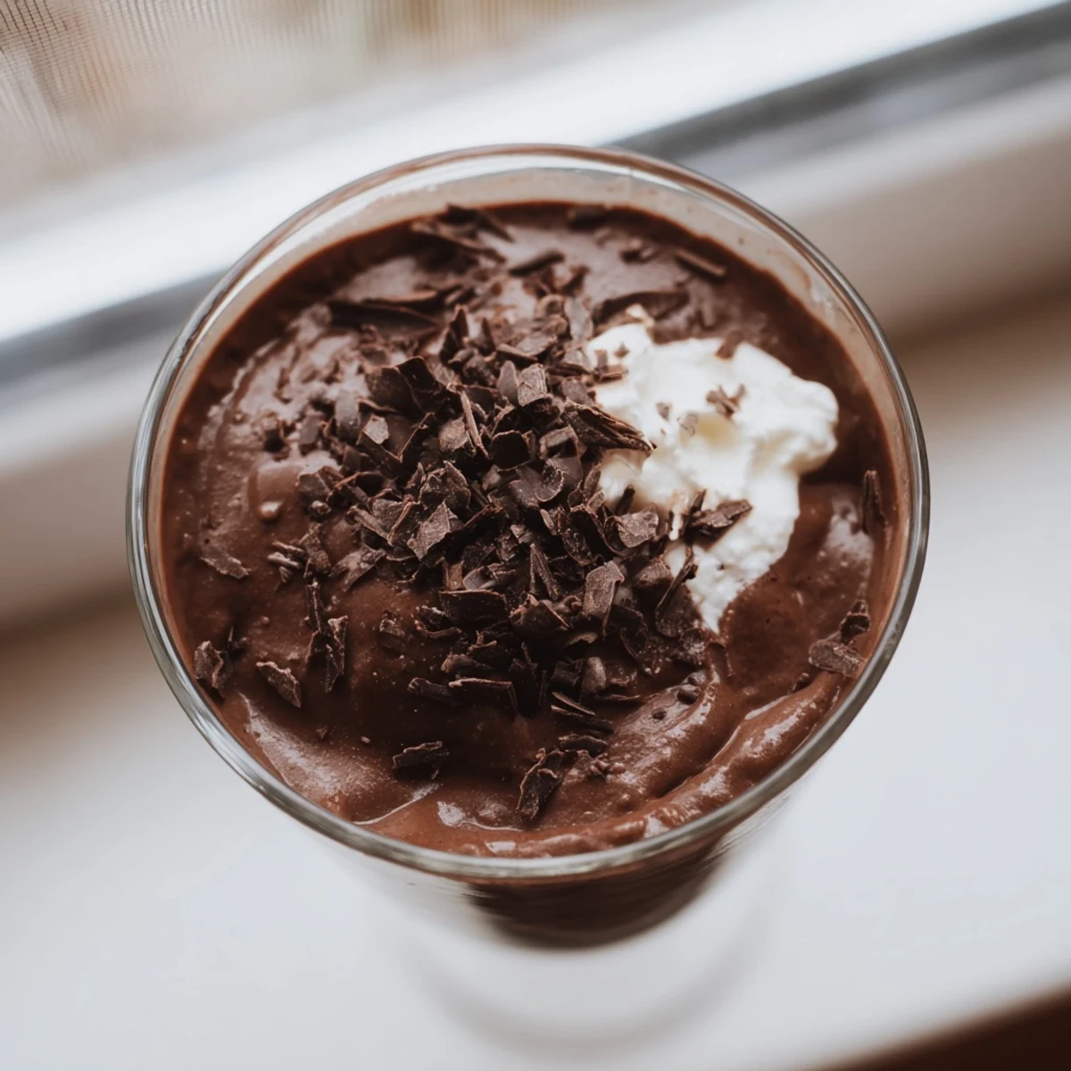 Silky chocolate mousse garnished with whipped cream in clear glass ramekins