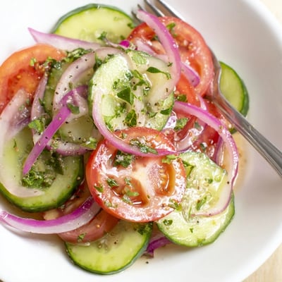 Bright Cucumber Tomato Salad tossed with red onion, parsley, and lemony olive oil  