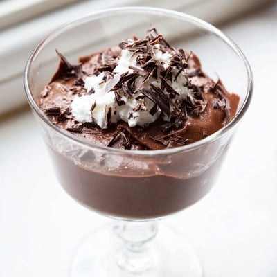 Creamy chocolate mousse spooned into dessert cups dusted with cocoa powder